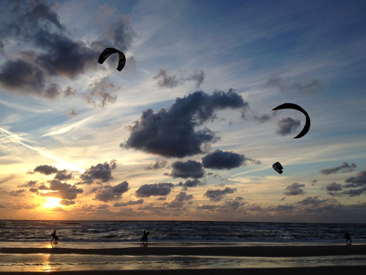 Foto van watersporters bij de ondergaande zon in Egmond aan zee